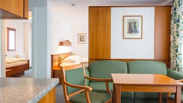 Ein Zimmer mit einem Bett, einem grünen Sofa, einem Holztisch und einem kleinen Schreibtisch mit Lampe.