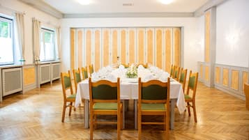 Comedor con una mesa redonda dispuesta para una comida, rodeada de sillas de madera con cojines verdes.