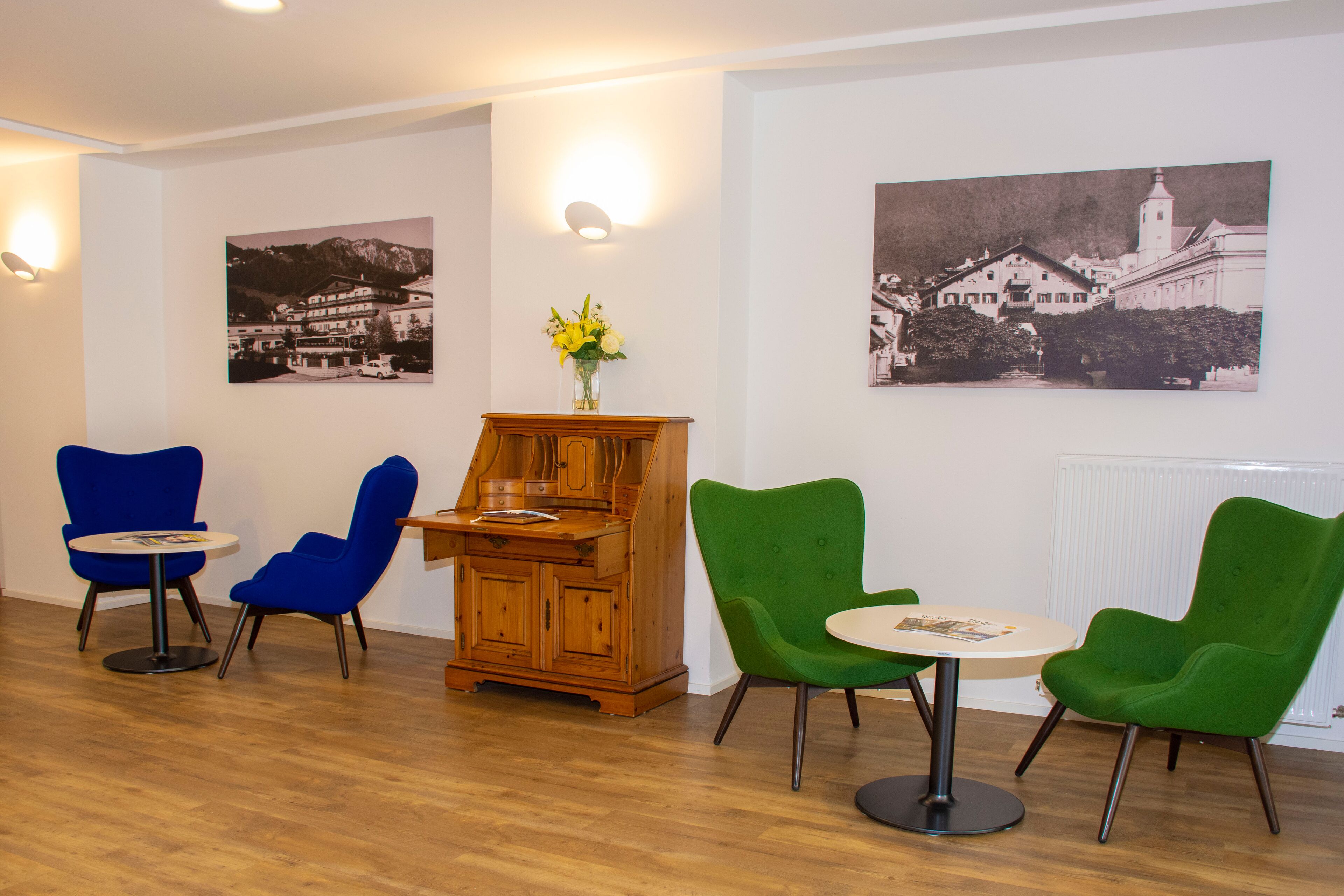 A room with wooden flooring, a wooden cabinet, and two round tables with chairs.