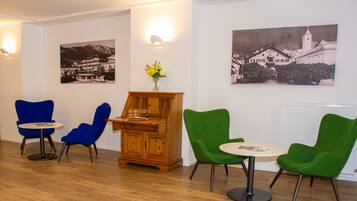 A room with wooden flooring, a wooden cabinet, and two round tables with chairs.