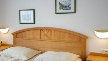 Habitación de hotel con cabecera de madera, dos camas, lámparas de noche y dos cuadros en la pared.