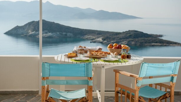 Une table dressée avec des aliments pour le petit-déjeuner, donnant sur un paysage montagneux.