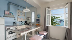 Une cuisine avec un four ancien, un plan de travail blanc et une fenêtre donnant sur la mer.