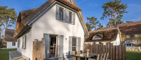 A house with a thatched roof, white exterior walls, and a wooden fence.