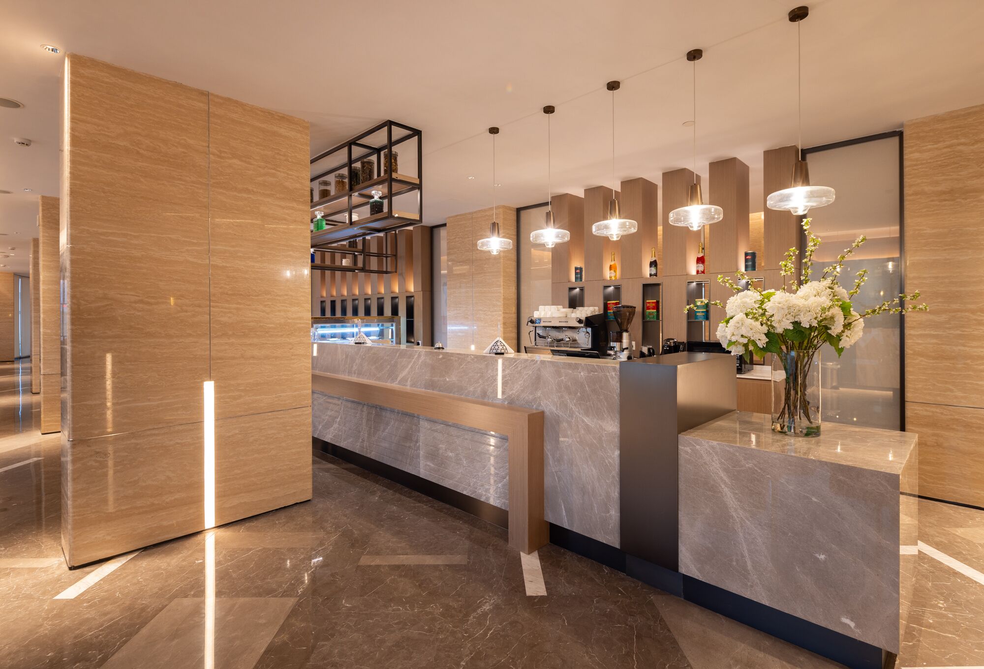 A modern reception area with a marble counter, pendant lighting, and a vase with flowers.
