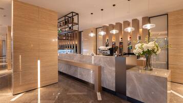A modern reception area with a marble counter, pendant lighting, and a vase with flowers.