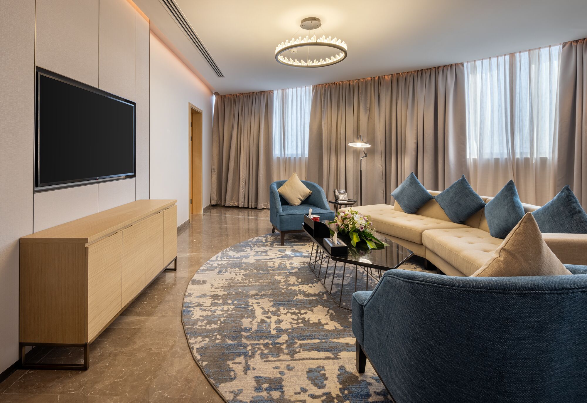 A modern living room with a flat-screen TV, a sofa, a coffee table, and a TV stand.