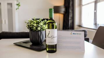 A bottle of wine, a potted plant, and a welcome card on a table.