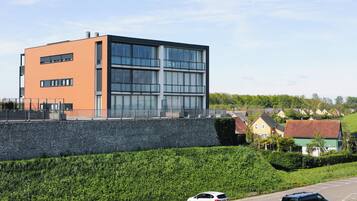 A modern building with a stone retaining wall and a parking lot with cars.