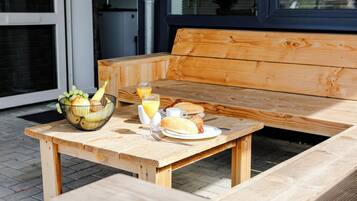 Una mesa de madera con alimentos para el desayuno, incluyendo un croissant, un vaso de jugo de naranja y un bol de fruta.
