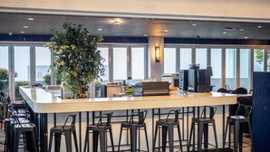 A bar area with a counter, stools, and a large potted plant.
