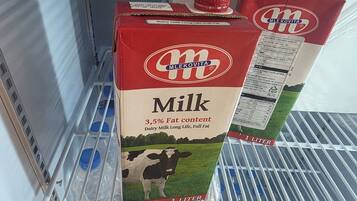 Una repisa de refrigerador con dos cartones de leche.