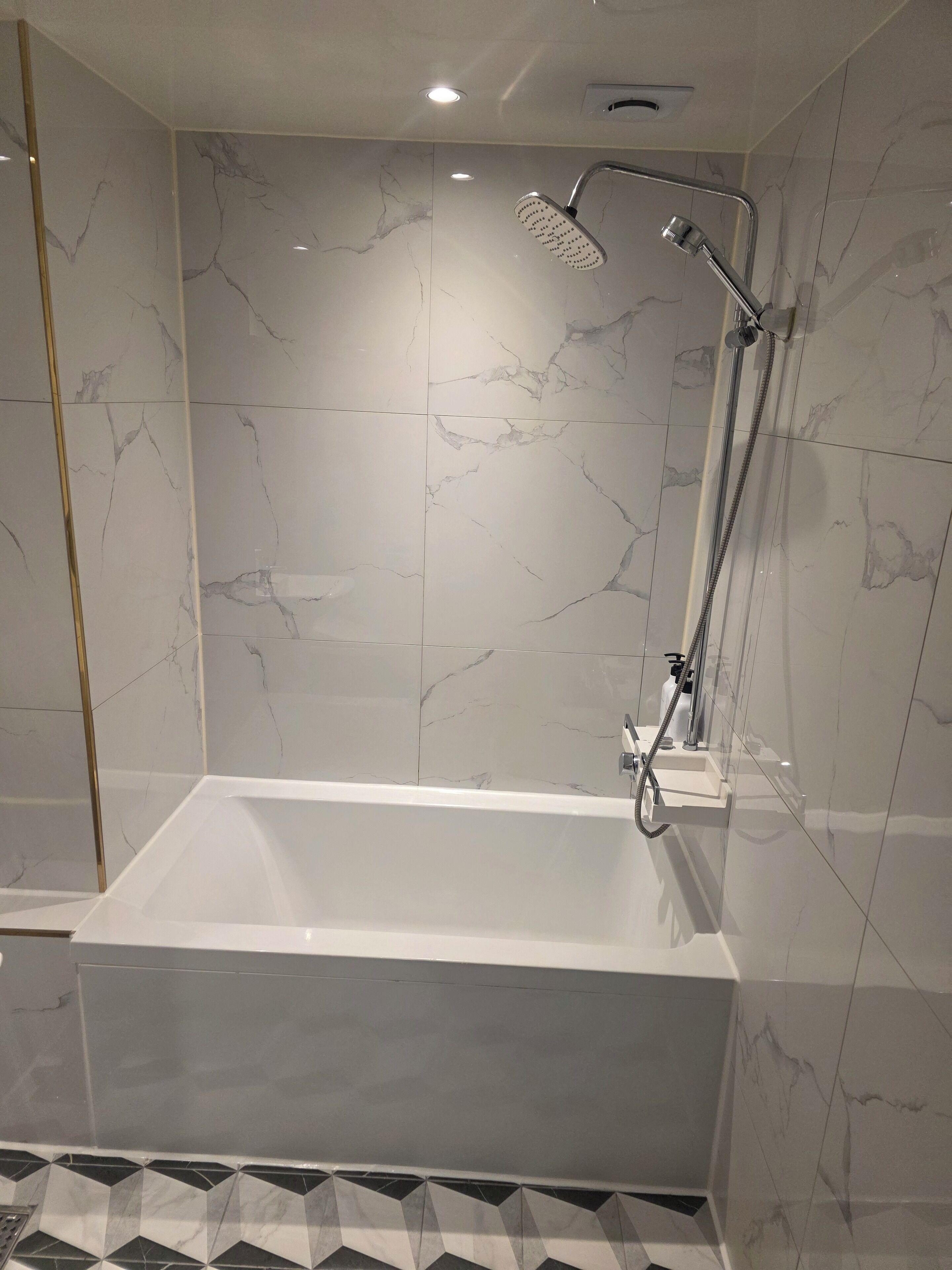 Une salle de bain moderne avec une baignoire sur pieds, une douchette et un robinet mural.