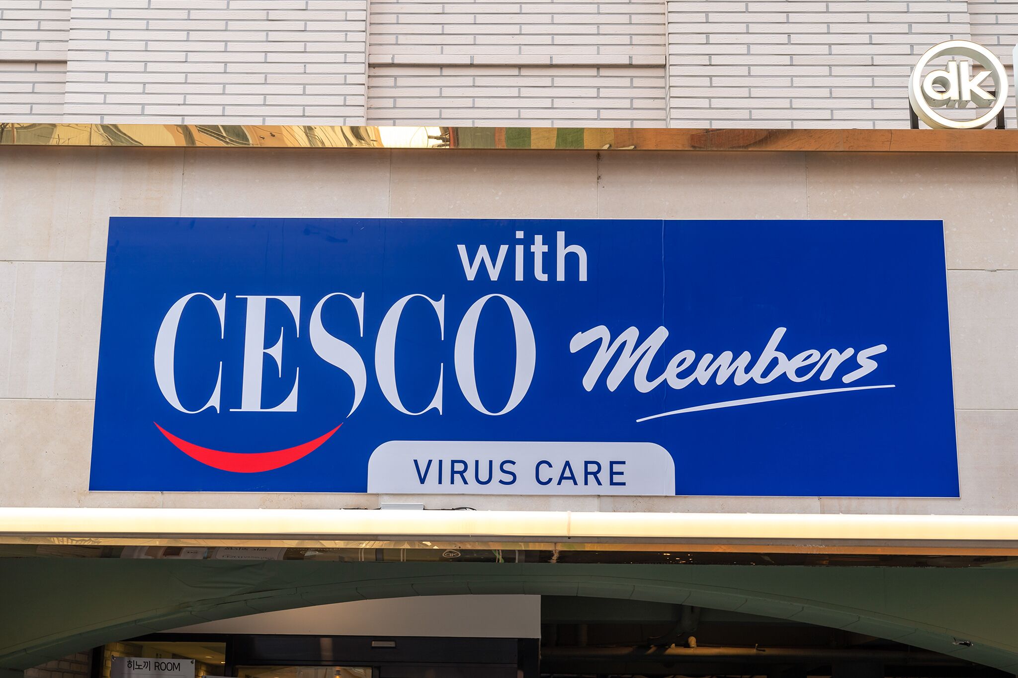 A blue sign with white text stating "with CESCO Members" and "VIRUS CARE" on a building facade.