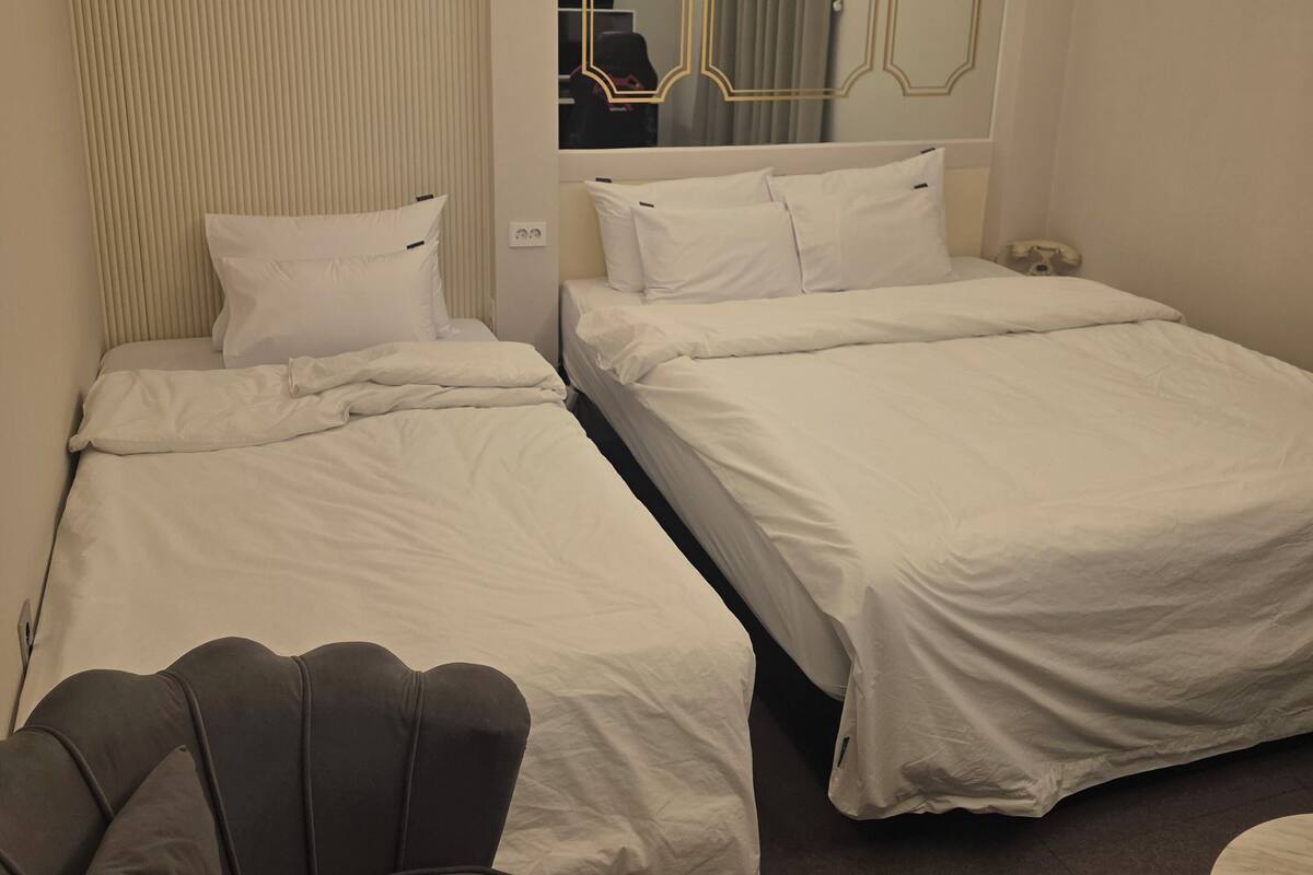 A hotel room with two beds, a sofa, a mirror, and a ceiling light fixture.