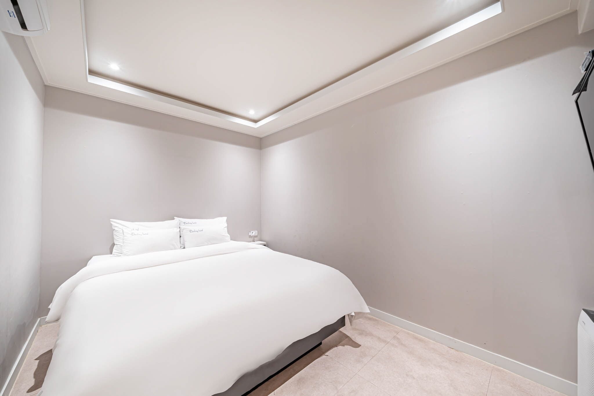 A bedroom with a large bed, a nightstand, and a ceiling light fixture.