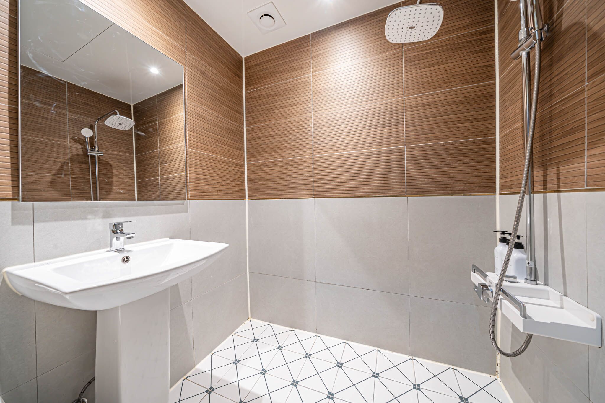 Une salle de bain moderne avec un lavabo blanc, une douchette à main et une douche murale.