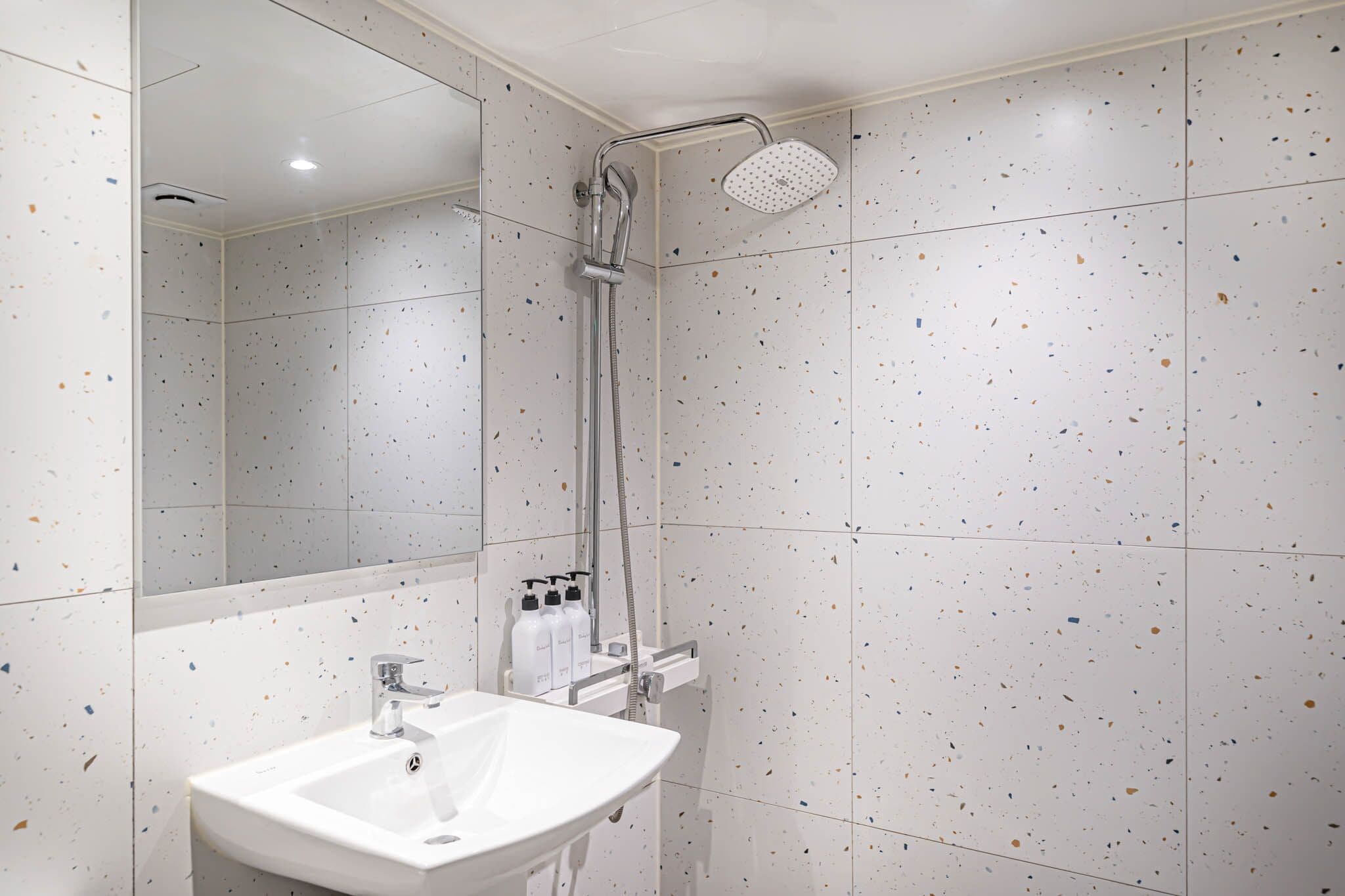 A bathroom with a shower, sink, and mirror.