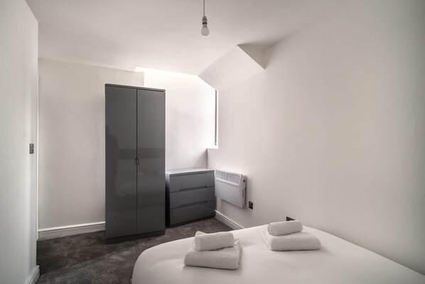 A modern bedroom with a large wardrobe, a bedside table, and a radiator.