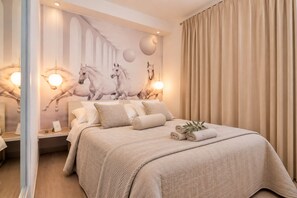 A hotel room with a large bed, a wall mural of horses, and a curtain.