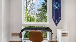 A room with a desk, chair, and a window with a view of trees. - The Boy Who Lived, Harry Potter's Sweet Suite (Seattle)