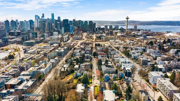 An aerial view of a city with dense urban development, including high-rise buildings and a prominent tower.