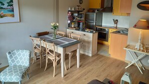A compact kitchen with modern appliances, a dining area with wooden chairs, and a small table with a vase of flowers. - Port Vannes - Bretagne SUD T2 Calme Avec Terrasse (Vannes)