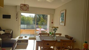 A bright living room with a dining area, large windows, and a view of the outdoors. - Port Vannes - Bretagne SUD T2 Calme Avec Terrasse (Vannes)