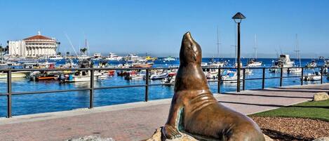 A harbor with boats, a statue of a sea lion, and a building with a red roof.
