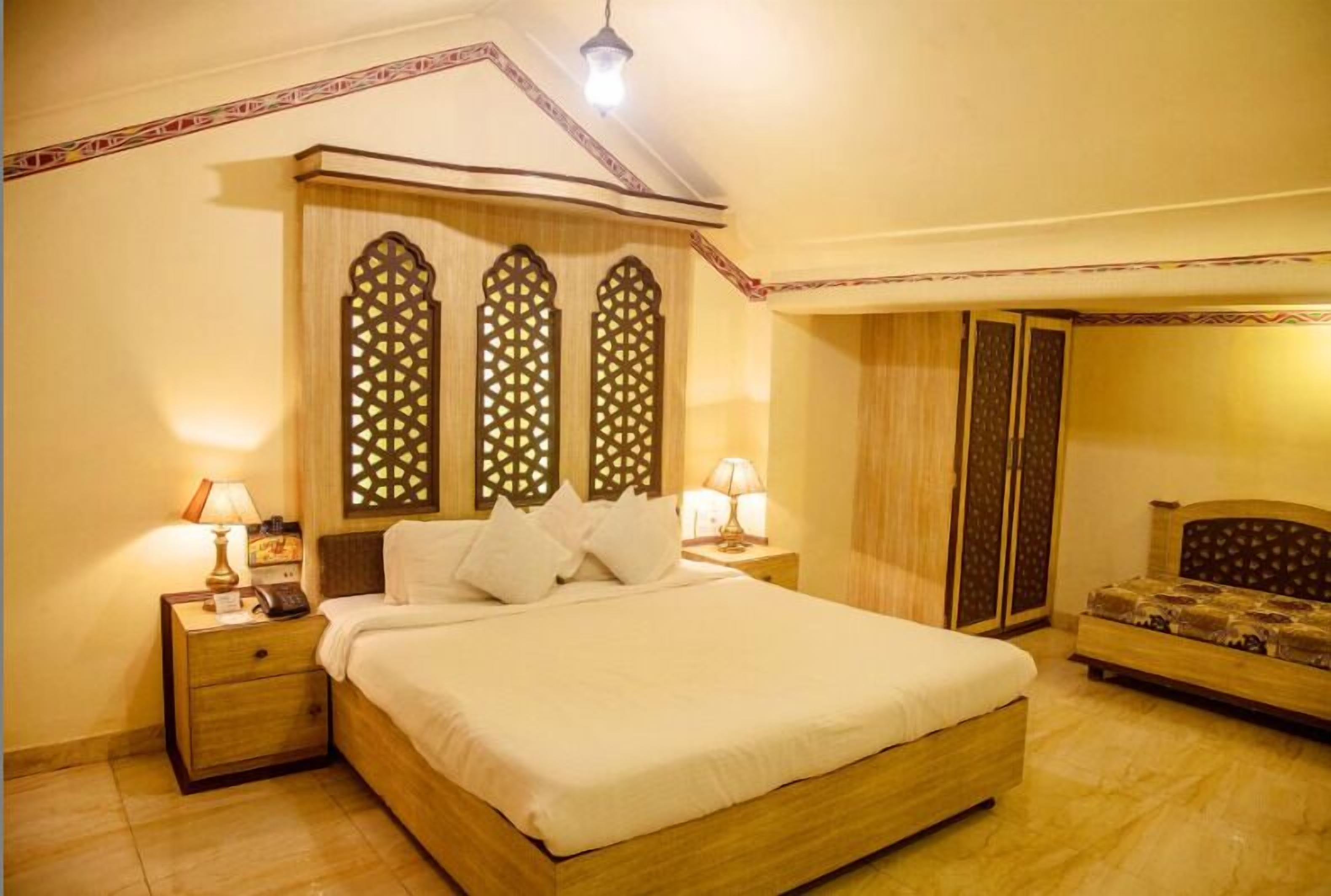Une chambre à coucher avec un grand lit, deux tables de chevet avec des lampes, une armoire et un petit canapé.
