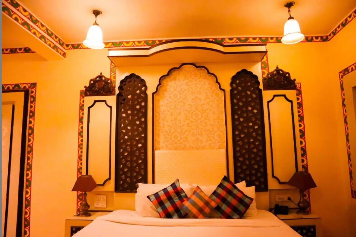 Habitación de hotel con cama, dos lámparas de noche y paneles decorativos en la pared.