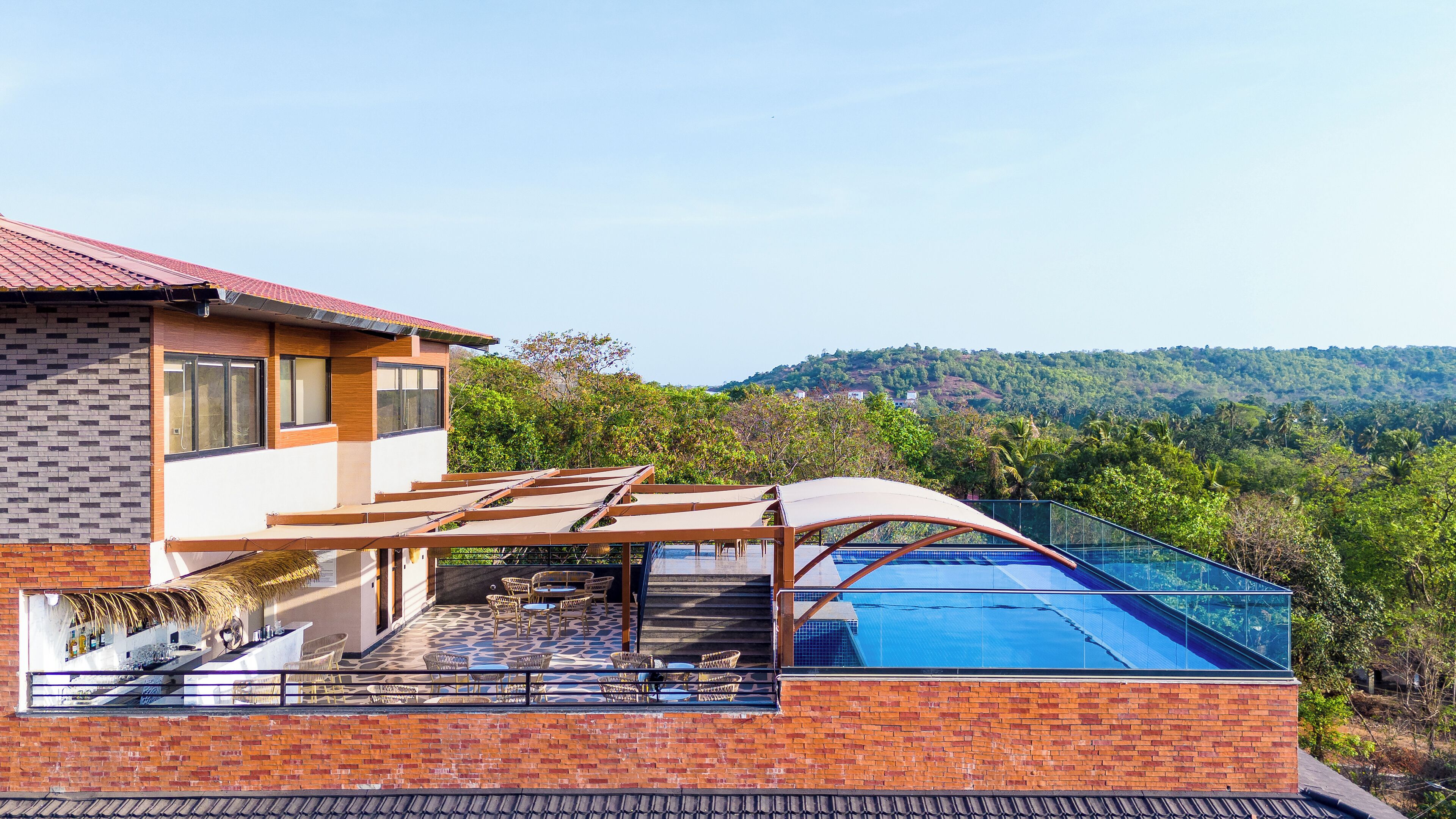A modern house with a swimming pool, outdoor seating, and a view of a hilly landscape.