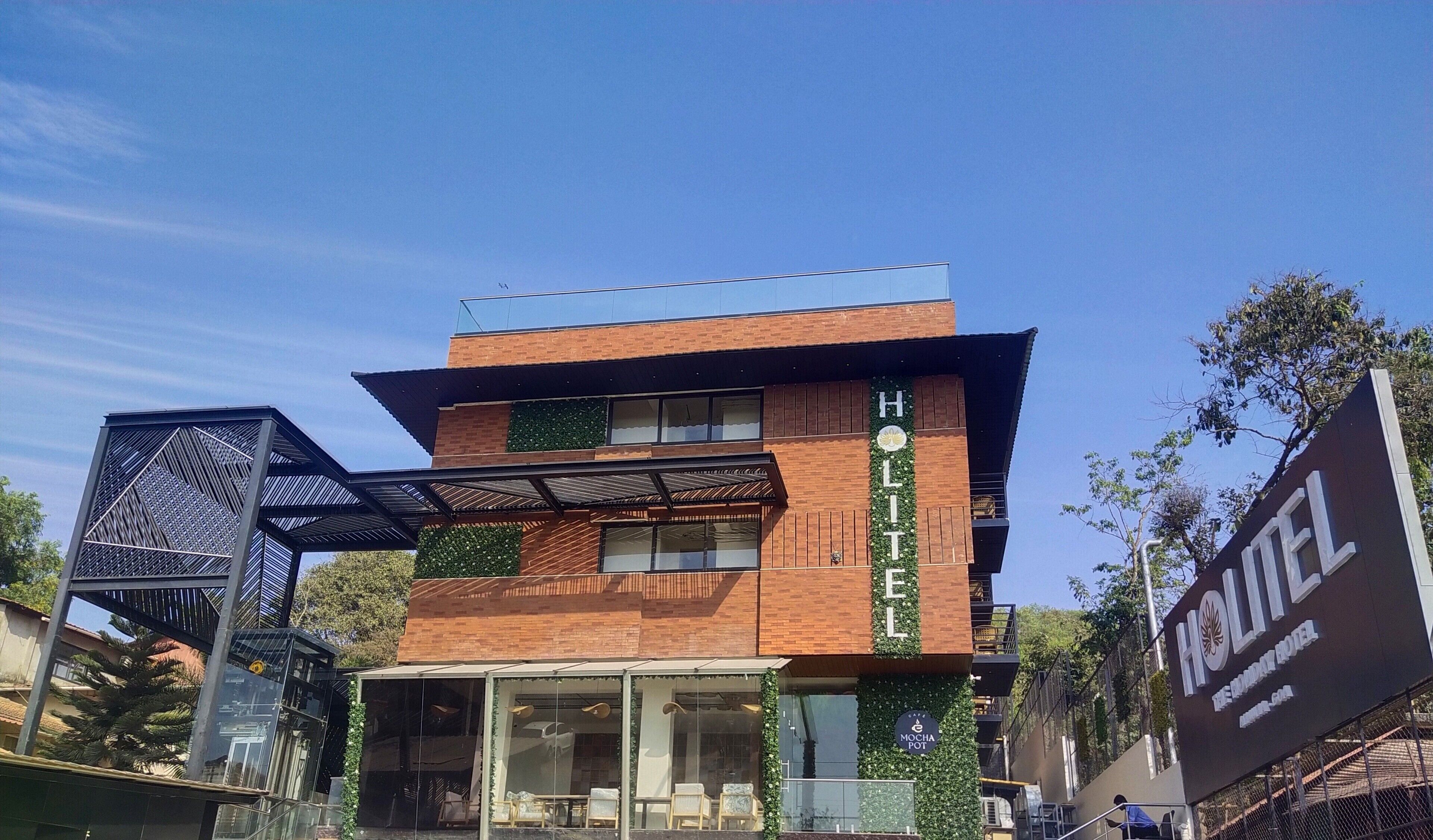 Un hôtel moderne avec une façade en briques, de grandes fenêtres et une terrasse sur le toit.