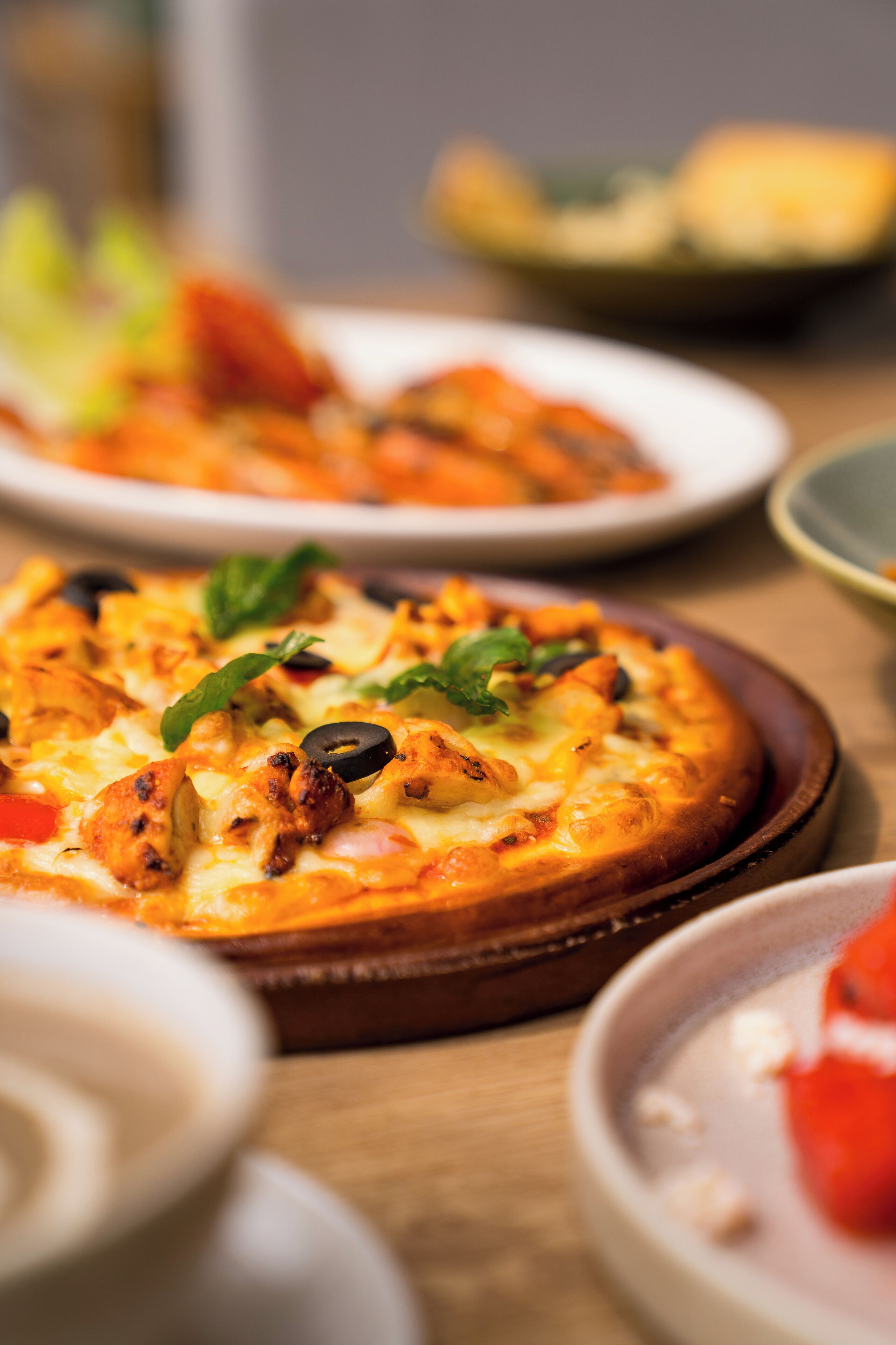 Une pizza garnie et une table en bois.