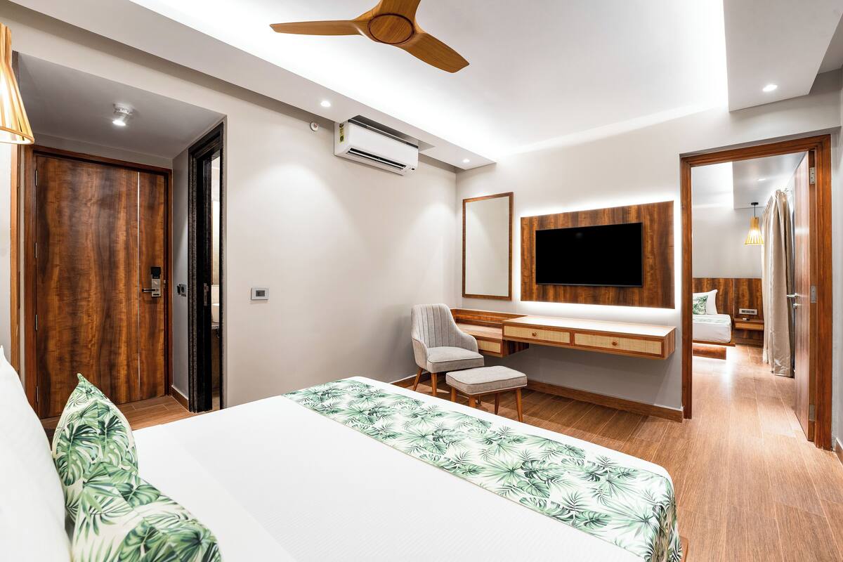 Una habitació d'hotel moderna amb un llit gran, una taula de treball, una cadira, un televisor i un aparell d'aire condicionat.