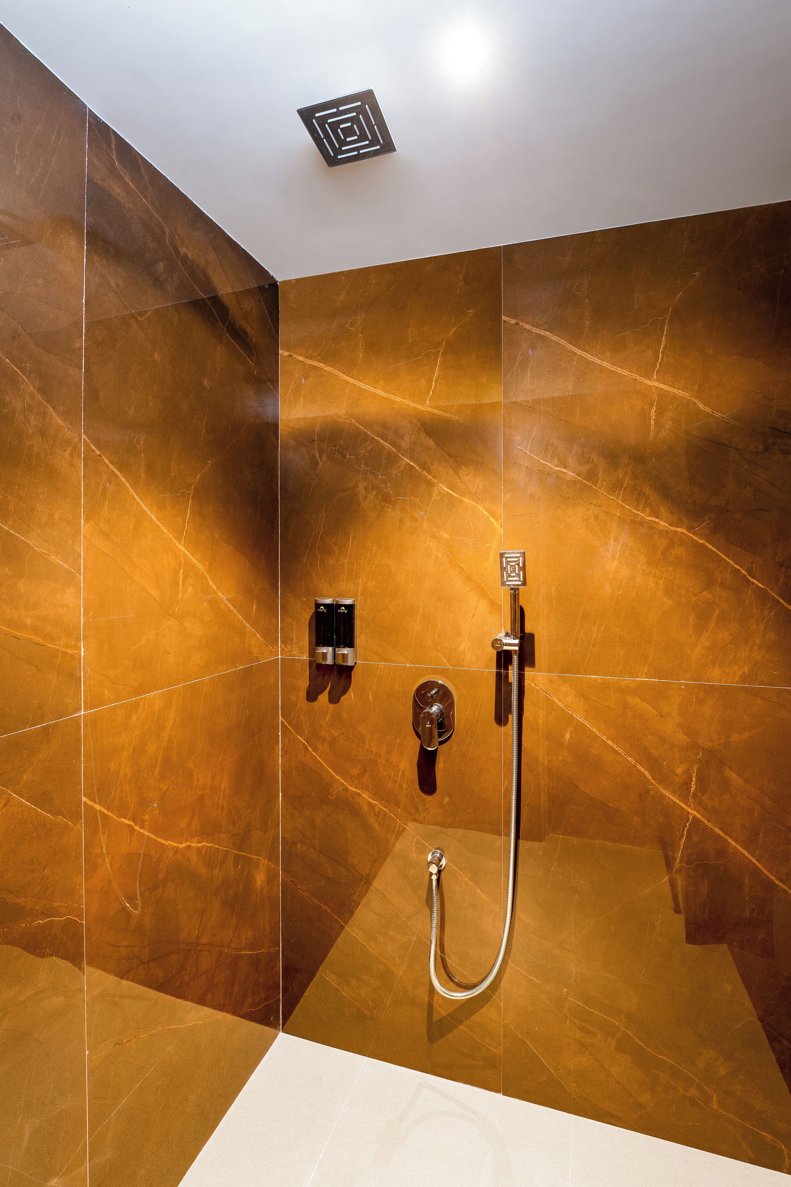 A bathroom with a shower, a towel rack, and a light fixture on the ceiling.