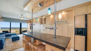 A modern kitchen with wooden cabinets, a granite countertop, and a built-in refrigerator.