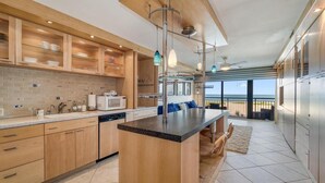A modern kitchen with wooden cabinets, a central island, and a view to the outside.
