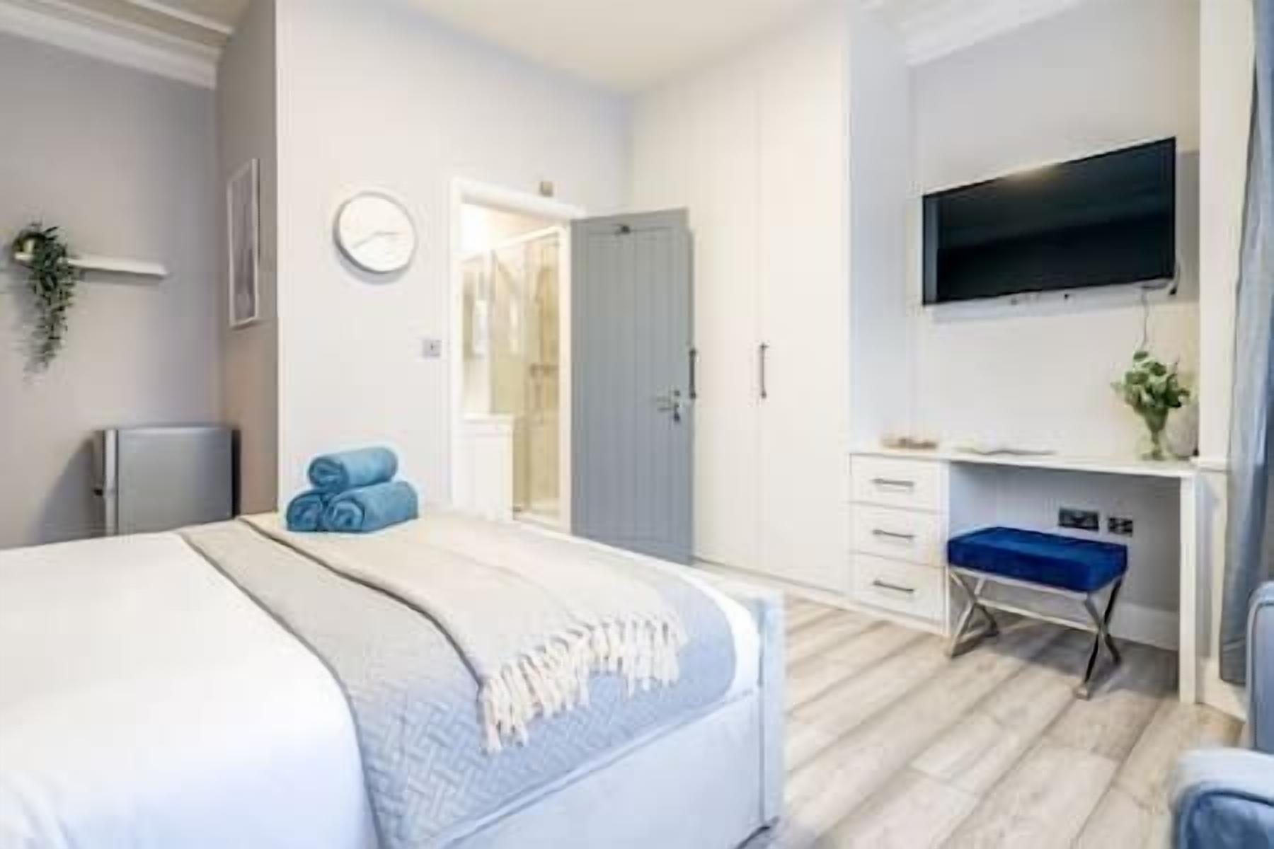 A bedroom with a bed, a desk, a chair, a TV, and a wardrobe.