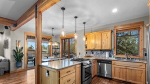 Una cocina moderna con armarios de madera, electrodomésticos de acero inoxidable e iluminación colgante.