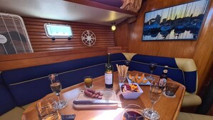 Ein Essbereich mit einem Holztisch, gedeckt für zwei Personen, mit einer Weinflasche, einer Schüssel mit Snacks und Weingläsern.