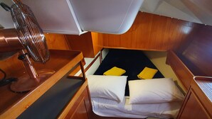 Ein gemütliches Blockhaus mit Bett, kleinem Tisch und Ventilator.