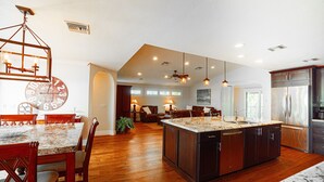 A spacious kitchen with a central island, wooden flooring, and modern lighting fixtures. - Private Riverfront Home - 1 mile to the Beach (Bonita Springs)