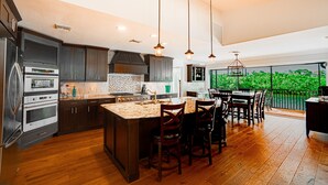 A modern kitchen with a large island, dark wood cabinets, stainless steel appliances, and pendant lighting. - Private Riverfront Home - 1 mile to the Beach (Bonita Springs)