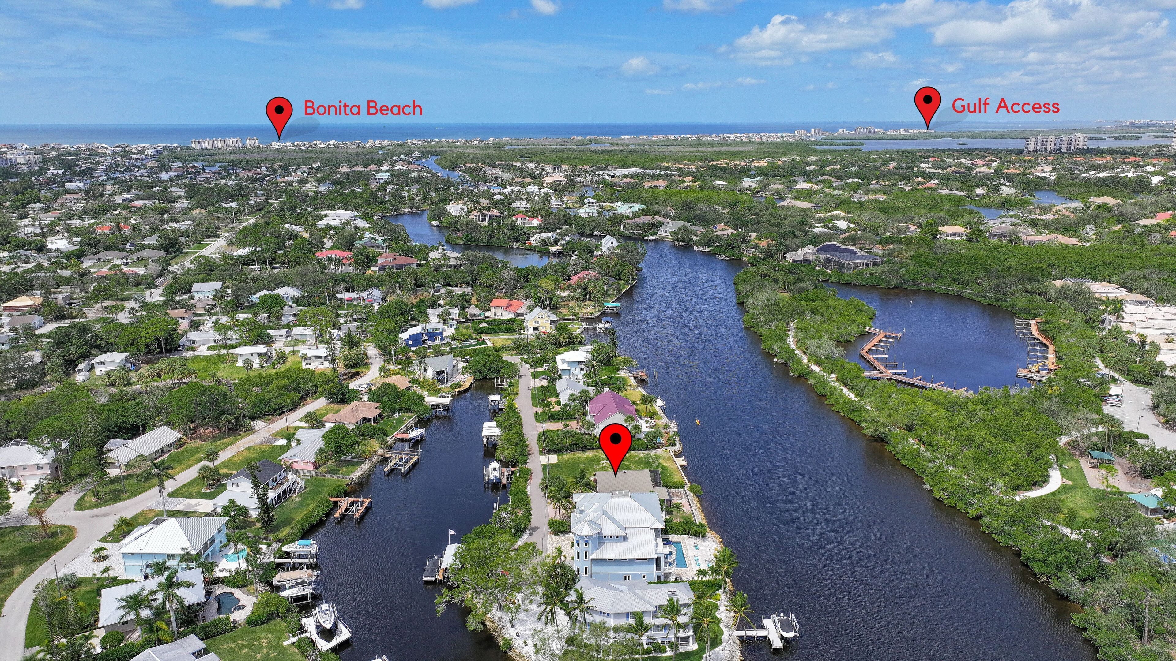 An aerial view of a coastal residential area with a river running through it, marked locations for Bonita Beach and Gulf Access, and a marina with boats docked.