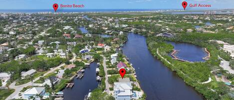 An aerial view of a coastal residential area with a river running through it, marked locations for Bonita Beach and Gulf Access, and a marina with boats docked.
