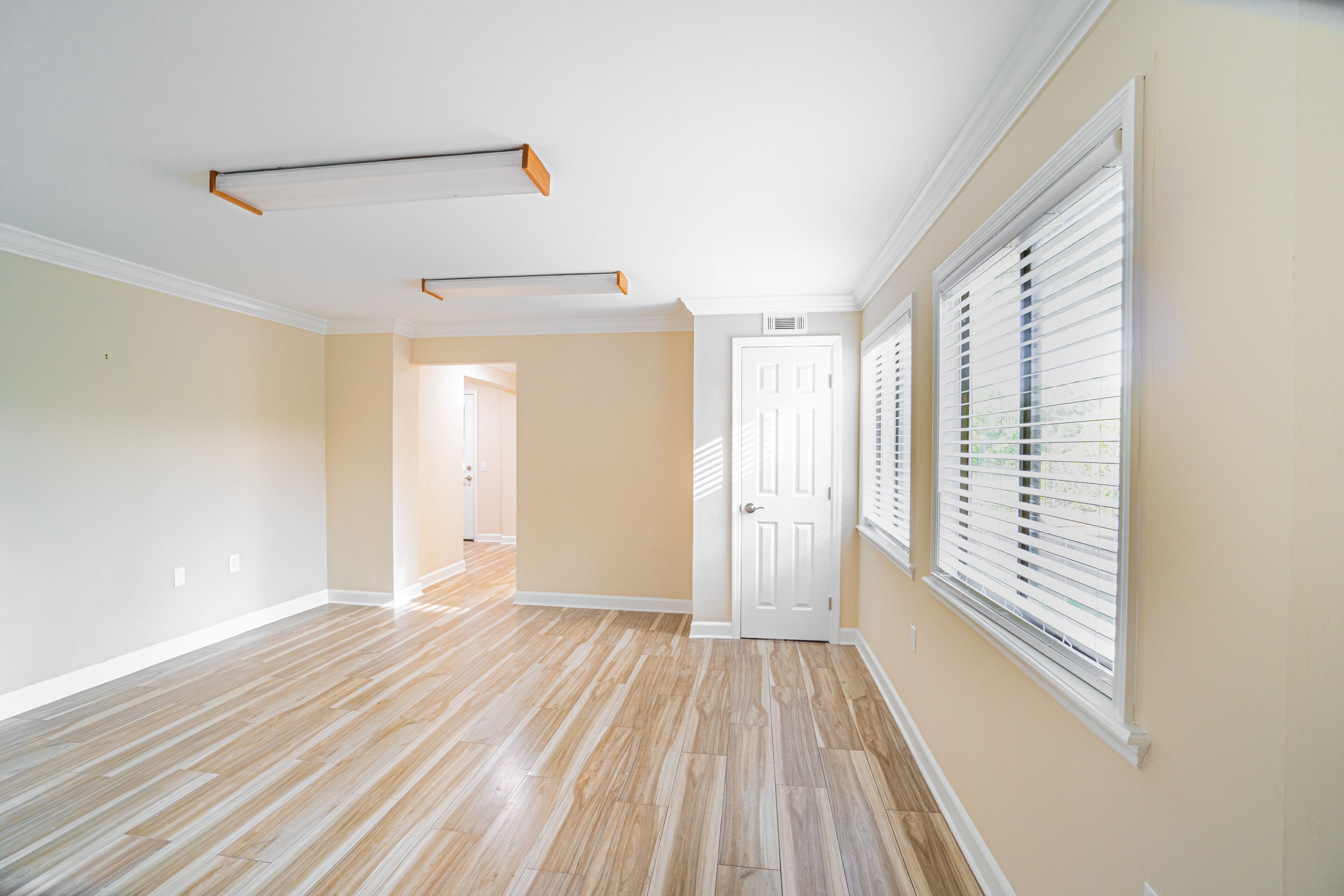 A spacious hallway with hardwood floors, beige walls, and white trim.
