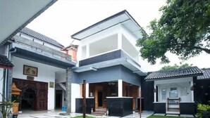 A modern two-story house with a covered patio area, a small garden, and a traditional entrance. - Omah Demak Ijo By Occupied  (Sleman)