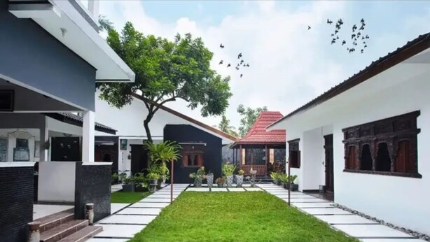 A courtyard with a central lawn, surrounded by buildings with a mix of modern and traditional architecture. - Omah Demak Ijo By Occupied  (Sleman)