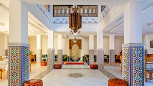 A spacious lobby with a central decorative area, a high ceiling with a chandelier, and patterned columns. - Villa Leila Farmhouse  (marrakech)